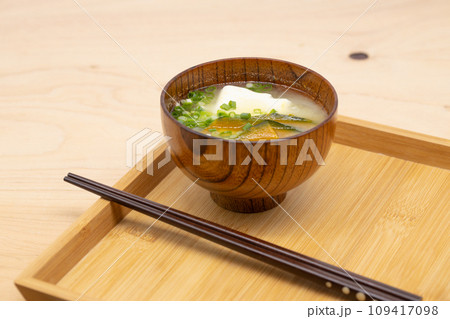 木製のトレーに配膳されているカボチャと豆腐の味噌汁 一膳の箸が添えられている 木製のトレーに配膳されているカボチャと豆腐の味噌汁 一膳の箸が添えられている 109417098