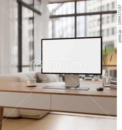 An empty PC computer screen mockup on a wooden desk in a modern room with large glass window wall. 109417187