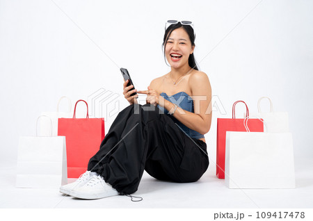 Elegant and happy Asian woman is enjoying shopping online on her smartphone, isolated background. Elegant and happy Asian woman is enjoying shopping online on her smartphone, isolated background. 109417478