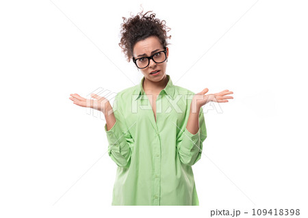 pretty young brunette curly woman in glasses is dressed in a green shirt on a white background with pretty young brunette curly woman in glasses is dressed in a green shirt on a white background with 109418398