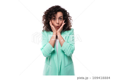 surprised young brunette curly businesswoman in a jacket on a white background surprised young brunette curly businesswoman in a jacket on a white background 109418884