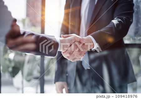 executives shaking hands in front of their manager and a colleague executives shaking hands in front of their manager and a colleague 109418976