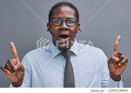young african american man surprised showing fingers up on gray background 109419000