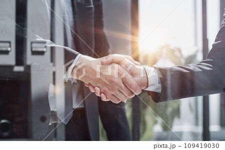 executives shaking hands in front of their manager and a colleague executives shaking hands in front of their manager and a colleague 109419030