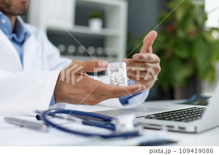 doctor's hand holding a bottle of pills close-up 109419086