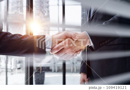 executives shaking hands in front of their manager and a colleague 109419121