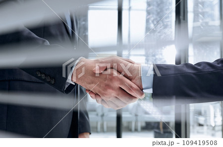 executives shaking hands in front of their manager and a colleague 109419508