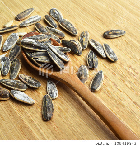 Roasted and salty organic sunflower seeds on wooden spoon Roasted and salty organic sunflower seeds on wooden spoon 109419843