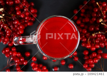 Hot viburnum tea in a glass cup with a double bottom on a black background. Hot viburnum tea in a glass cup with a double bottom on a black background. 109421461