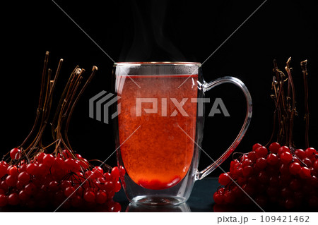 Hot viburnum tea in a glass cup with a double bottom on a black background. 109421462