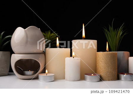 Burning candles and an aroma lamp on a black background. Incense, background for meditation and yoga. Burning candles and an aroma lamp on a black background. Incense, background for meditation and yoga. 109421470