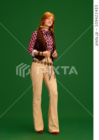 Adorable female fashion model with red hair dressed old-fashioned western style outfit posing against green studio background. Adorable female fashion model with red hair dressed old-fashioned western style outfit posing against green studio background. 109422483