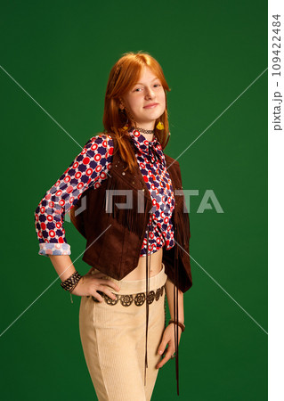 Half-length portrait of calm beautiful female fashion model with red hair dressed old-fashioned western style outfit posing against green studio background. Half-length portrait of calm beautiful female fashion model with red hair dressed old-fashioned western style outfit posing against green studio background. 109422484