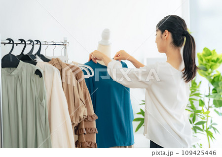 アパレルショップで商品を陳列する女性店員 アパレルショップで商品を陳列する女性店員 109425446
