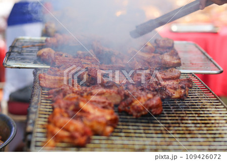 Closeup of man cooking grilled ribs on the grill in the market Closeup of man cooking grilled ribs on the grill in the market 109426072