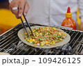 Man cooking grilled vietnamese pancake with eggs sausages and sauces in food festival 109426125