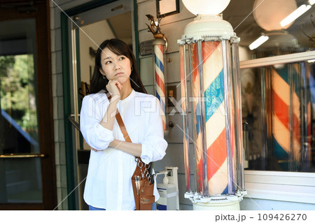 理容室の前で悩むアジア人の女性の理容師 109426270