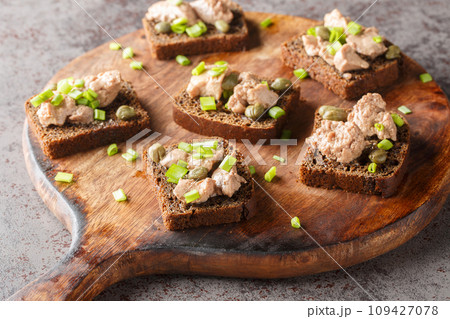 Homemade rye bread sandwiches with cod liver, capers and green onions close-up on a cutting board. Horizontal Homemade rye bread sandwiches with cod liver, capers and green onions close-up on a cutting board. Horizontal 109427078