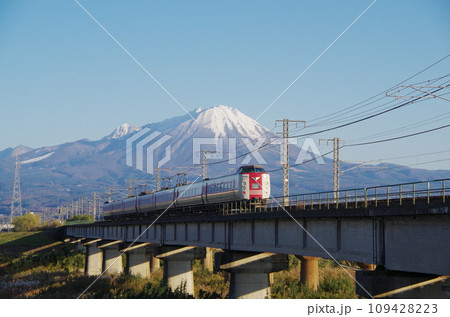 冠雪の大山を背景に日野川の長い鉄道橋梁を駆け抜ける標準ゆったりやくも色の381系特急やくも号 109428223