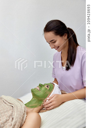 female beautician applies the mask to the face of beautiful woman in the spa salon. facial skin care female beautician applies the mask to the face of beautiful woman in the spa salon. facial skin care 109428693