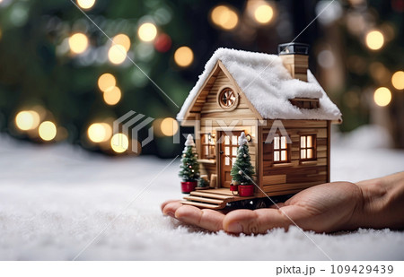 A realistic wooden modern tiny house in a small size in Christmas decor and snow, on the palm of hand. Festive mood and comfort, gift, mortgage, housing, rent, moving in New Year. Copy space A realistic wooden modern tiny house in a small size in Christmas decor and snow, on the palm of hand. Festive mood and comfort, gift, mortgage, housing, rent, moving in New Year. Copy space 109429439