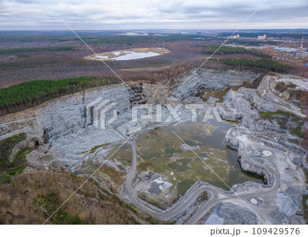 Stone quarry in the forest. Flying over the autumn mixed forest during sunset. The surroundings of Yekaterinburg. Ural, Russia, Aerial View Stone quarry in the forest. Flying over the autumn mixed forest during sunset. The surroundings of Yekaterinburg. Ural, Russia, Aerial View 109429576