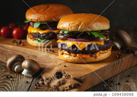 Two delicious homemade burgers of beef, cheese and mushrooms on an wooden table. Fat unhealthy food 109430098