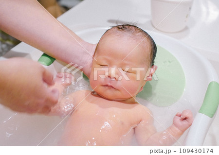 キッチンシンクのベビーバスで沐浴する新生児期の赤ちゃん キッチンシンクのベビーバスで沐浴する新生児期の赤ちゃん 109430174