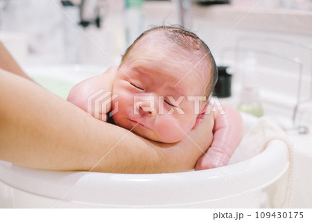 キッチンシンクのベビーバスで沐浴する赤ちゃん 109430175