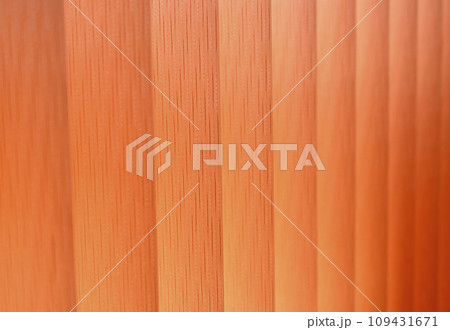 Background of vertical orange blinds curtains. Pleated roller blinds. Orange striped background. 109431671