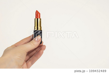 A woman's hand holds a tube of red lipstick, A woman's hand holds a tube of red lipstick, 109432489