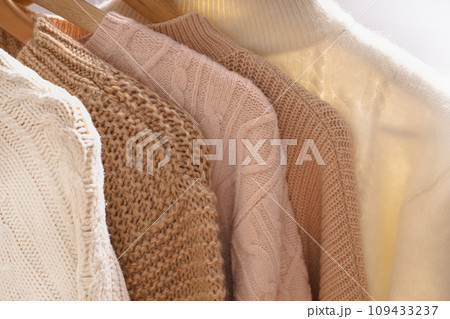 Winter sweaters hang in a row on a hanger, shoulders close-up Winter sweaters hang in a row on a hanger, shoulders close-up 109433237