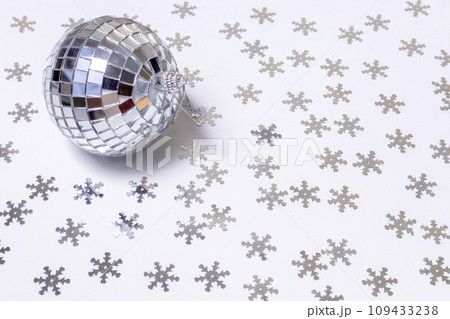 The disco ball lies on a white background strewn with silver snowflakes. New Year and Christmas background 109433238