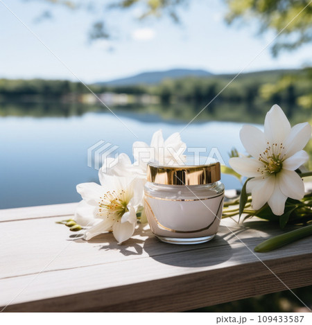 cream in a jar on table by lake with flowers, 109433587
