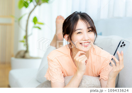 部屋でスマホを操作する若い女性 109433624