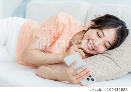 部屋でスマホを操作する若い女性 部屋でスマホを操作する若い女性 109433628