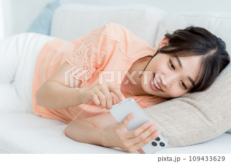 部屋でスマホを操作する若い女性 部屋でスマホを操作する若い女性 109433629