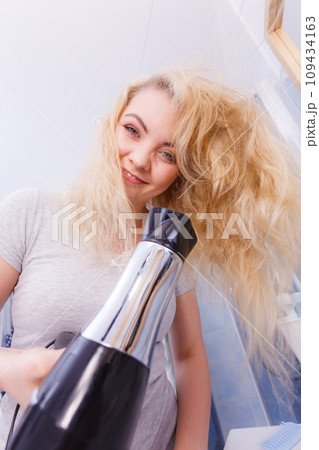 Woman drying hair in bathroom Woman drying hair in bathroom 109434163