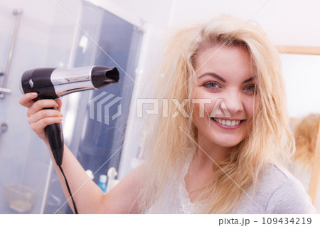 Woman drying hair in bathroom Woman drying hair in bathroom 109434219