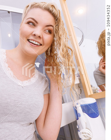 Woman looking at herself in bathroom mirror Woman looking at herself in bathroom mirror 109434352