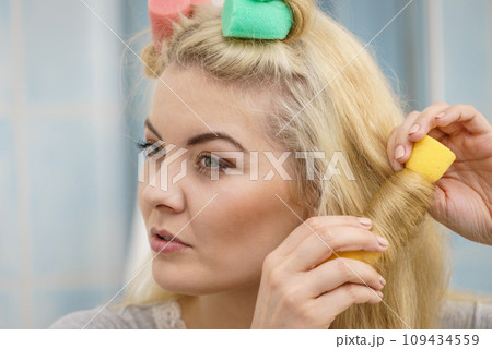 Blonde woman using hair rollers 109434559