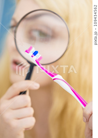 Woman looking at toothbrush through loupe 109434562