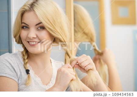 Woman making braid on blonde hair 109434563