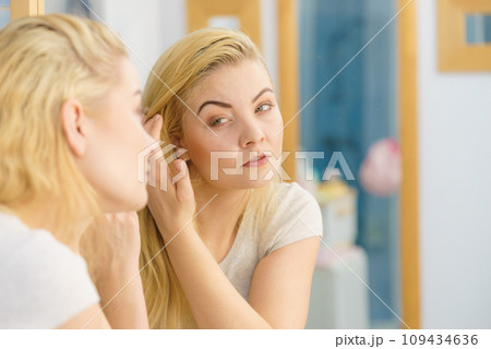Woman looking at her skin in mirror 109434636
