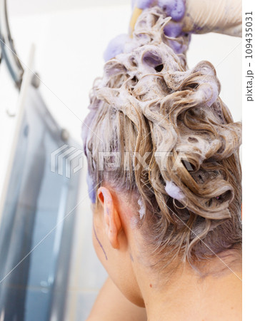 Woman applying toner shampoo on her hair Woman applying toner shampoo on her hair 109435031