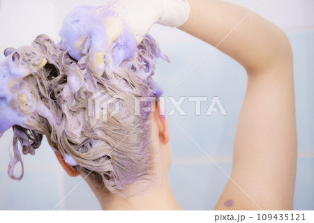 Woman applying toner shampoo on her hair Woman applying toner shampoo on her hair 109435121