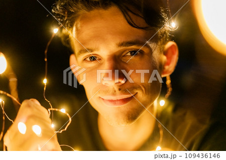 young guy at night holding glowing garlands in his hands, selective focus 109436146