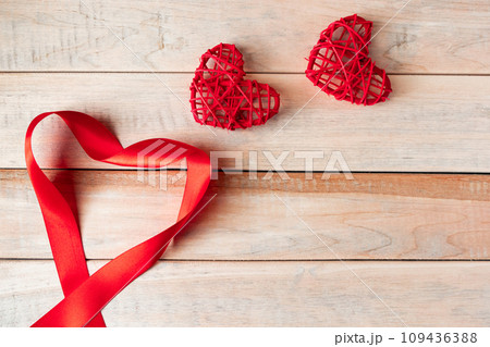 Red silk ribbon in shape of a heart on a wooden background. Valentine's day concept. Place for text. 109436388