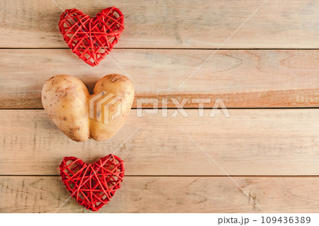Heart shaped potatoes on a wooden background. Valentine's day, place for text. Ugly vegetables. 109436389