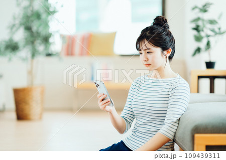 リビングでスマホを操作する若い女性。 リビングでスマホを操作する若い女性。 109439311